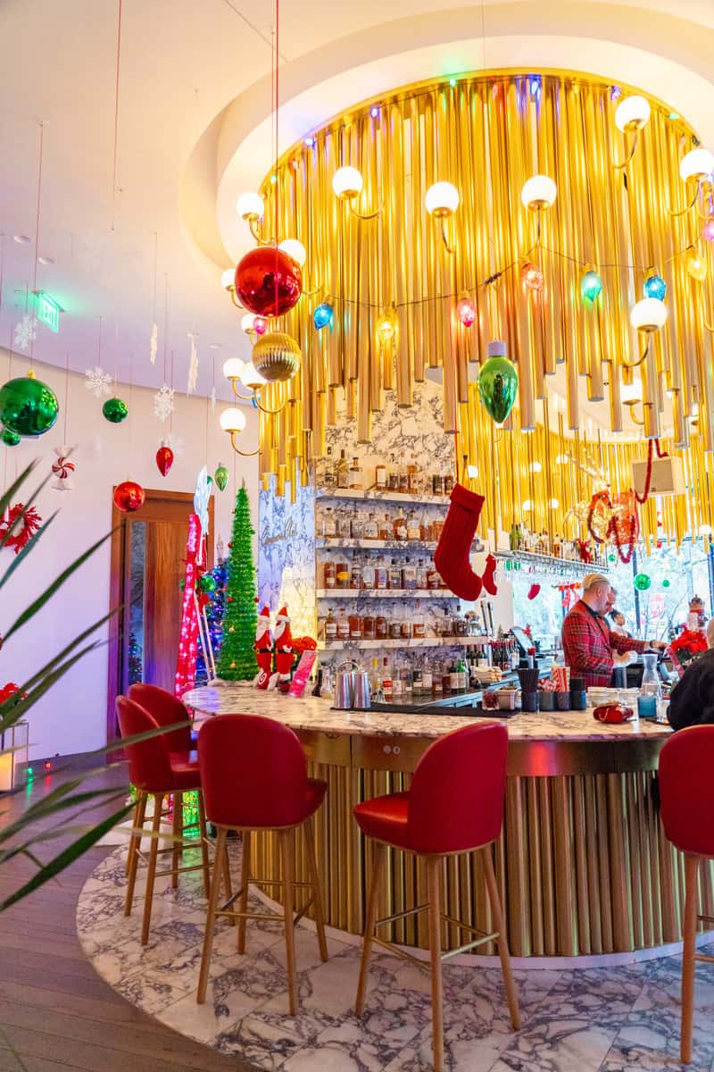 A bar in holiday golden decorations on ceiling and red chairs 