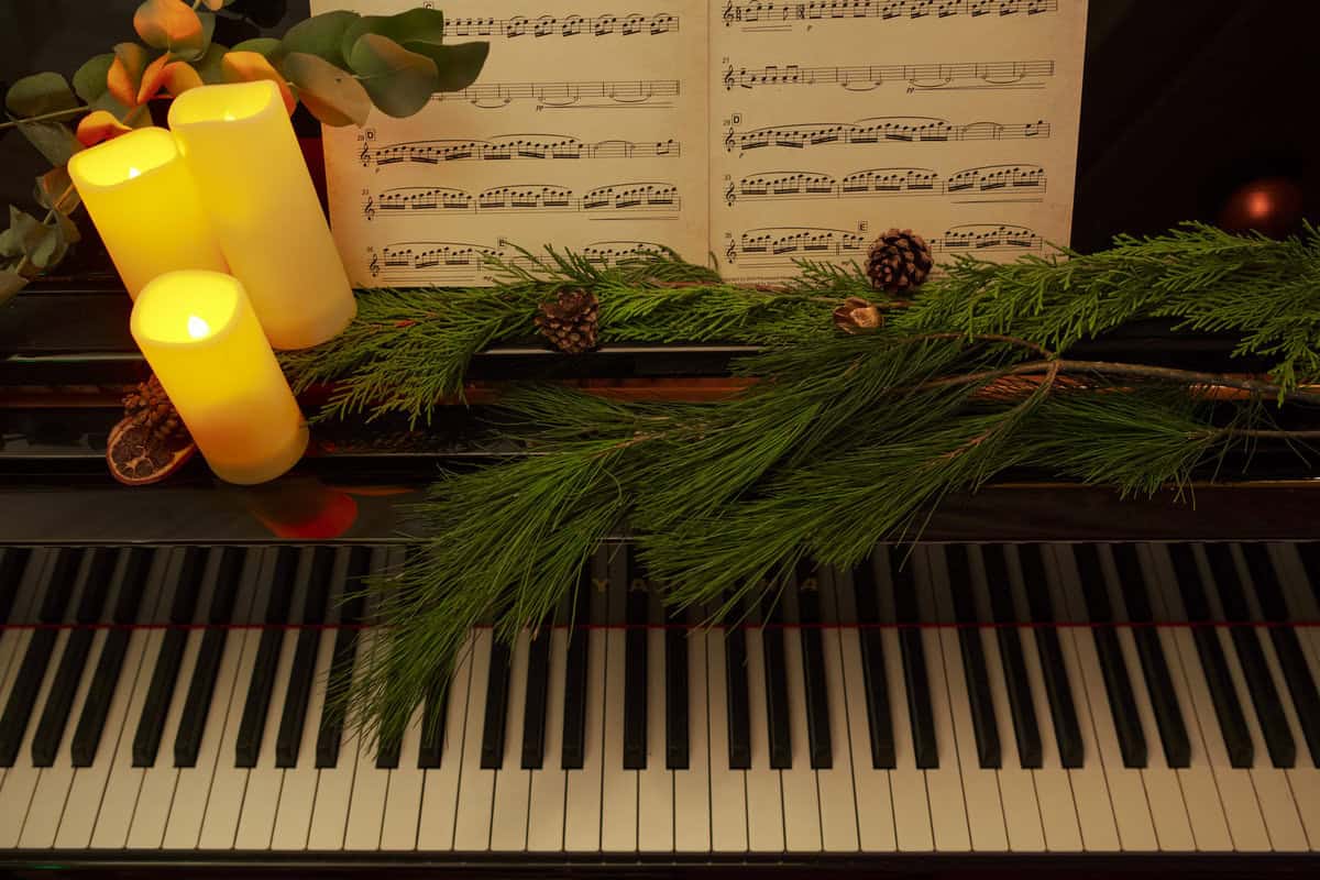 Piano keys with lit candles, pine branches, and sheet music