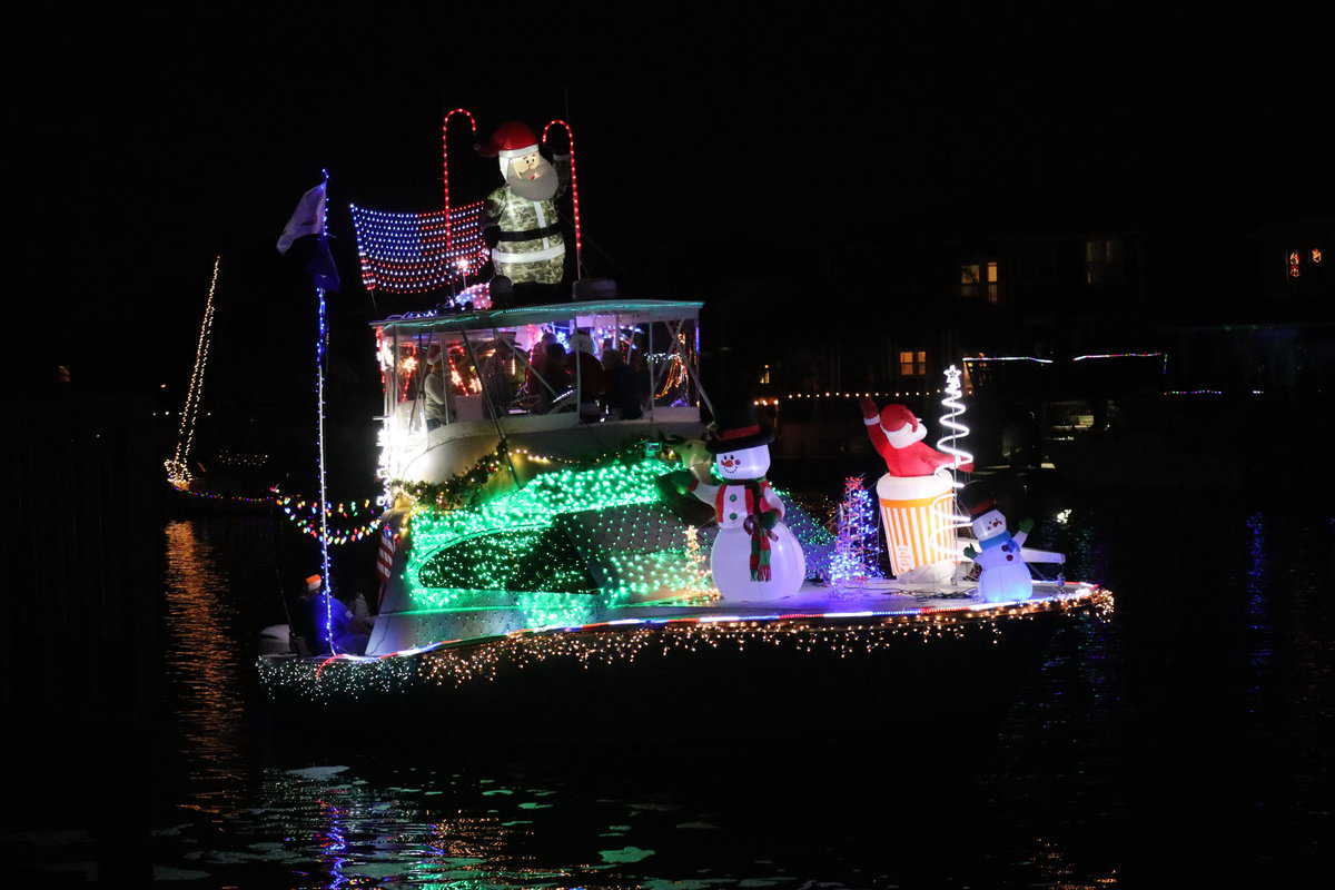 A boat adorned with festive lights and Christmas decorations floats at night.