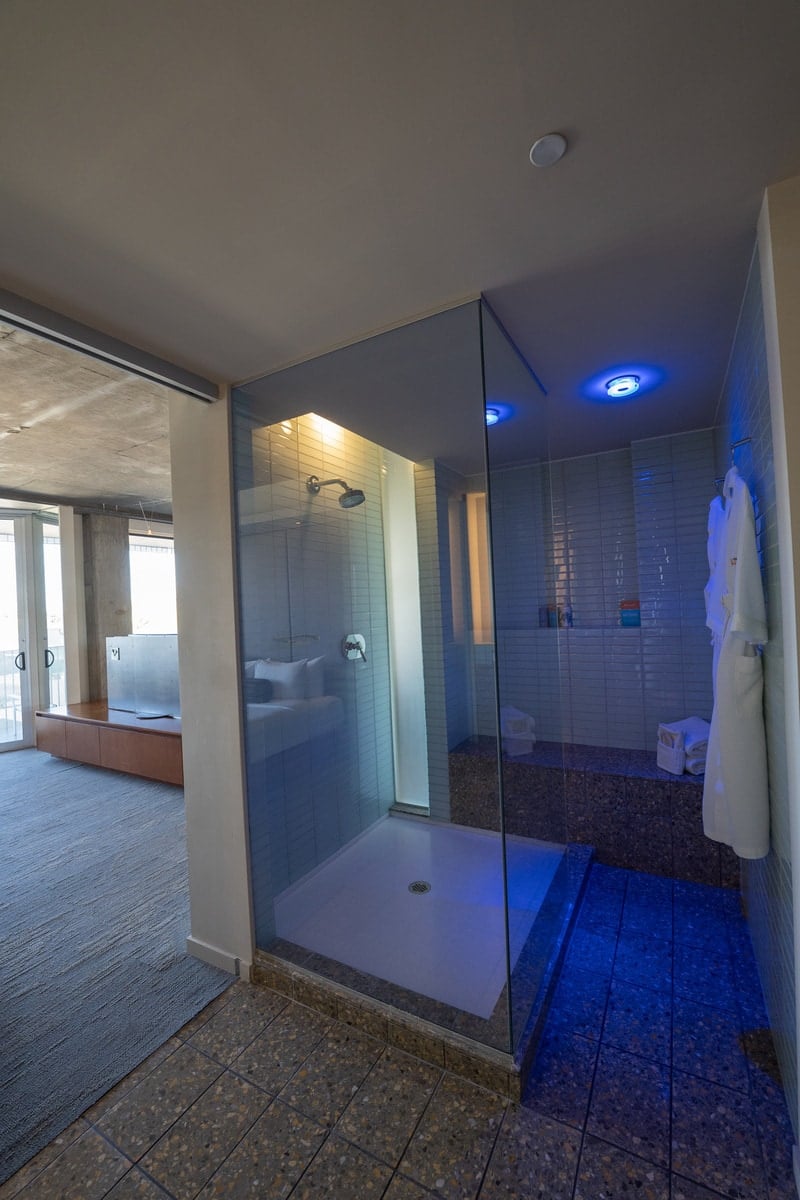 A walk-in shower with blue overhead lighting