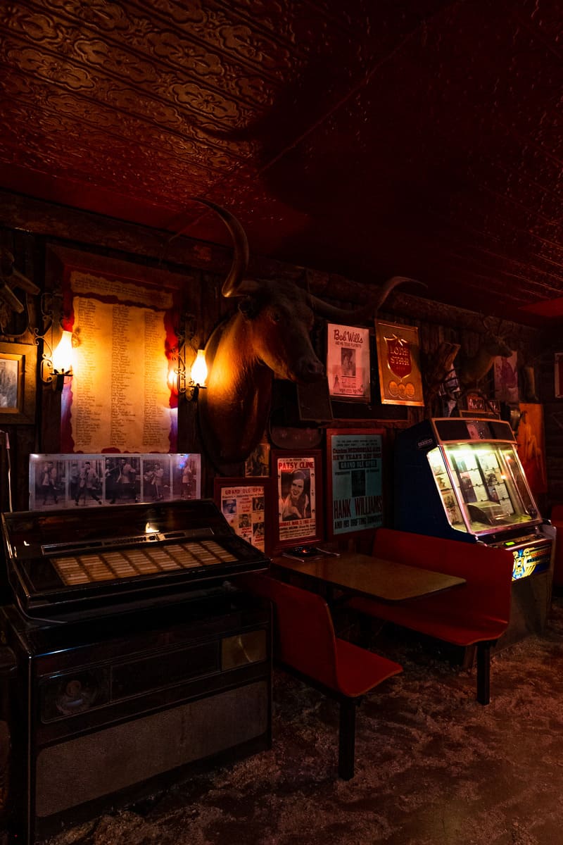 Interior of a dimly lit bar with a bull head mounted on the wall above an old jukebox.