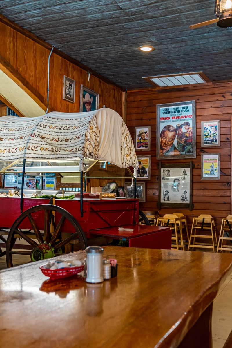 A cloth-covered wagon in the middle of the dining room with a salad bar in it