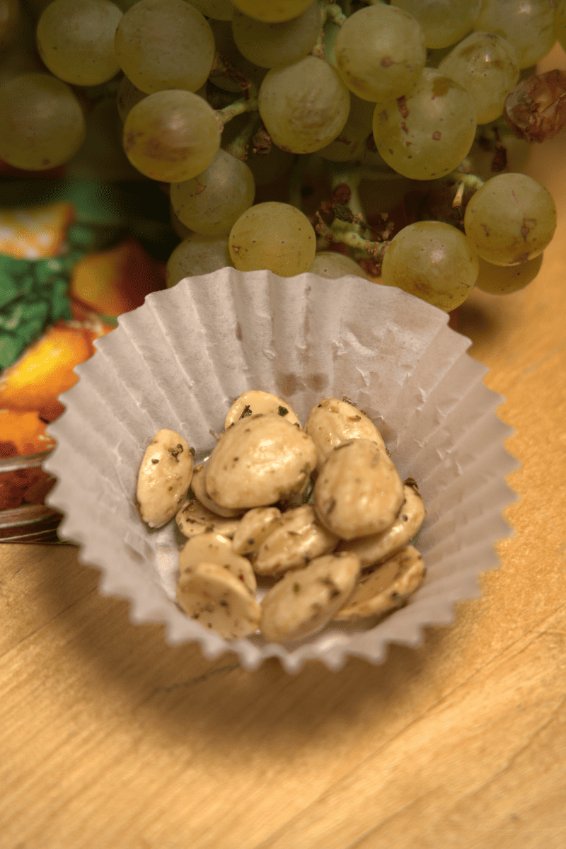 A nuts inside a paper cup with grapes in the background.