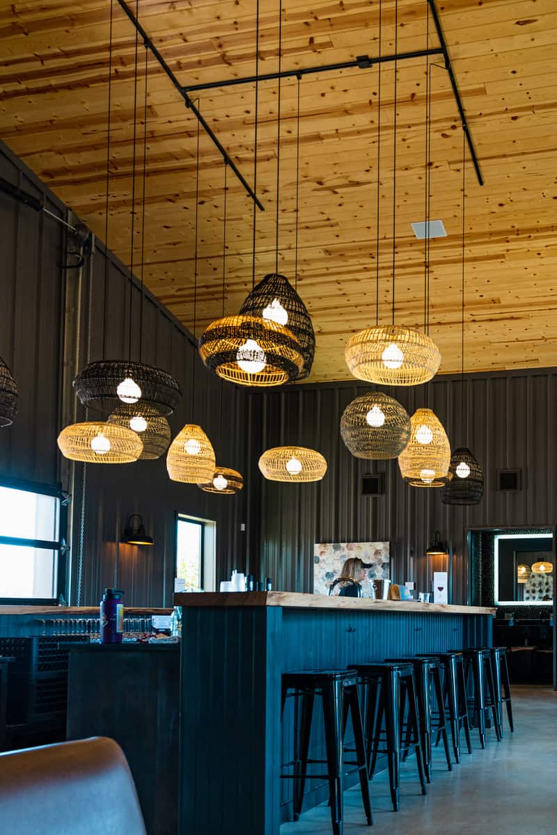 A cozy restaurant with warm wooden ceilings and plenty of lights illuminating the space.