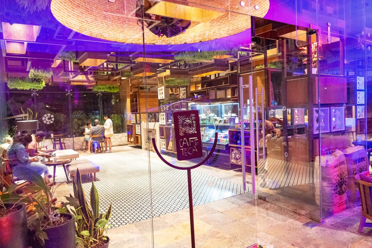 A coffee shop with a spacious glass wall and a vibrant purple light illuminating the interior.