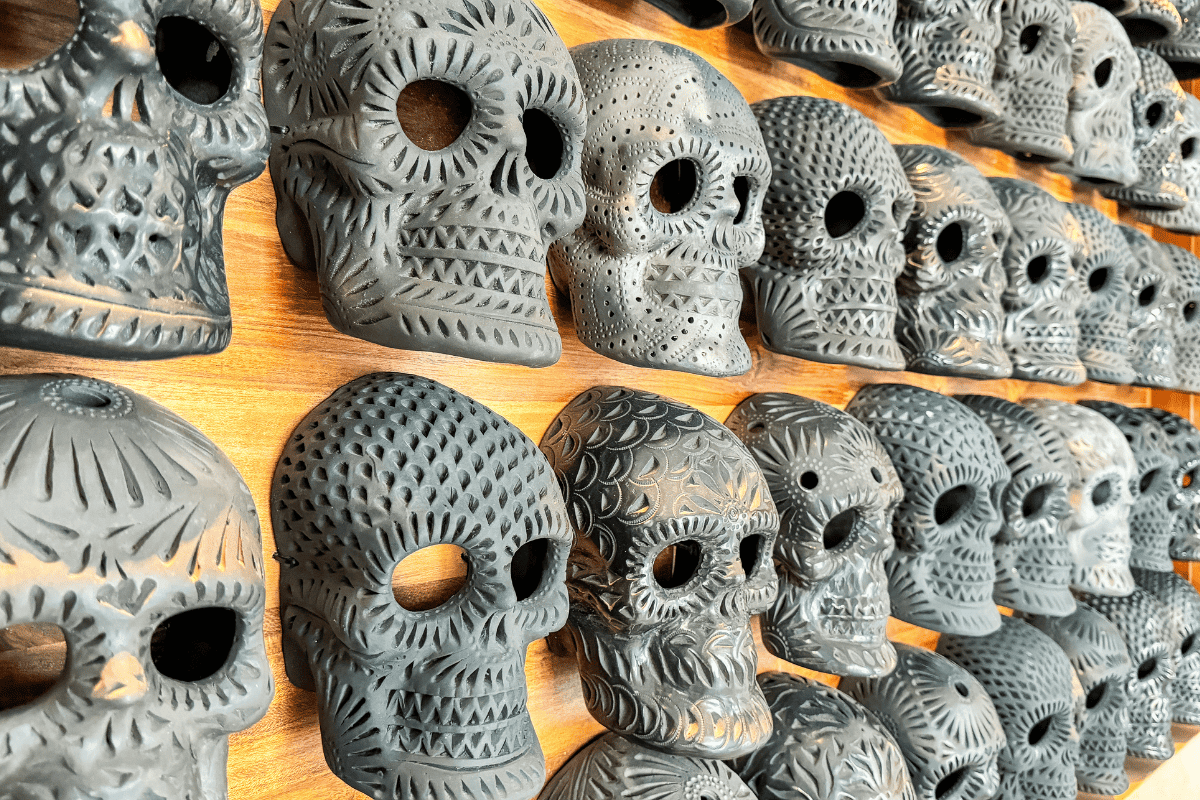 A monochrome wall of skulls masks.