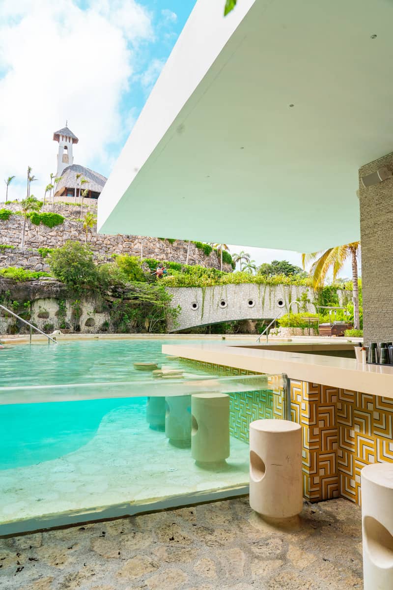 A pool with a bar and stools, offering a refreshing and relaxing atmosphere for guests to enjoy.