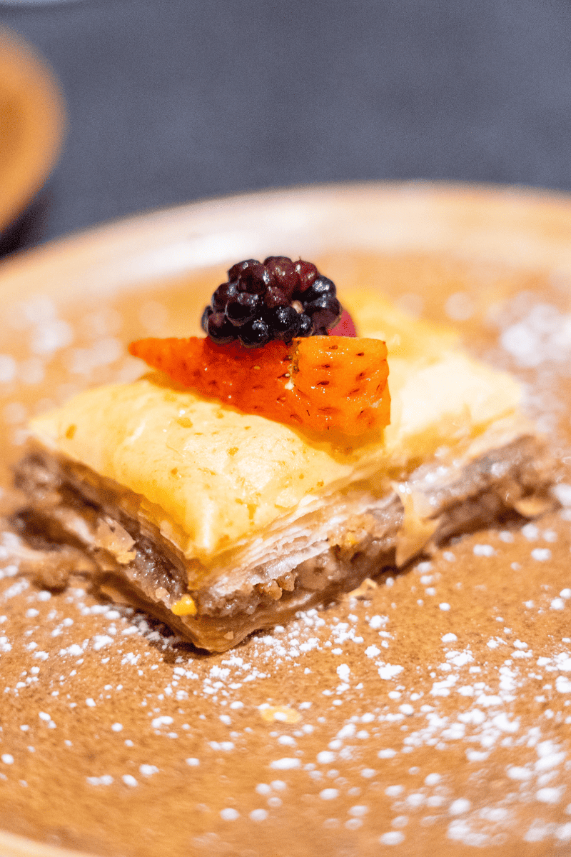 Plate with a dessert topped with sliced fruit and powdered sugar.