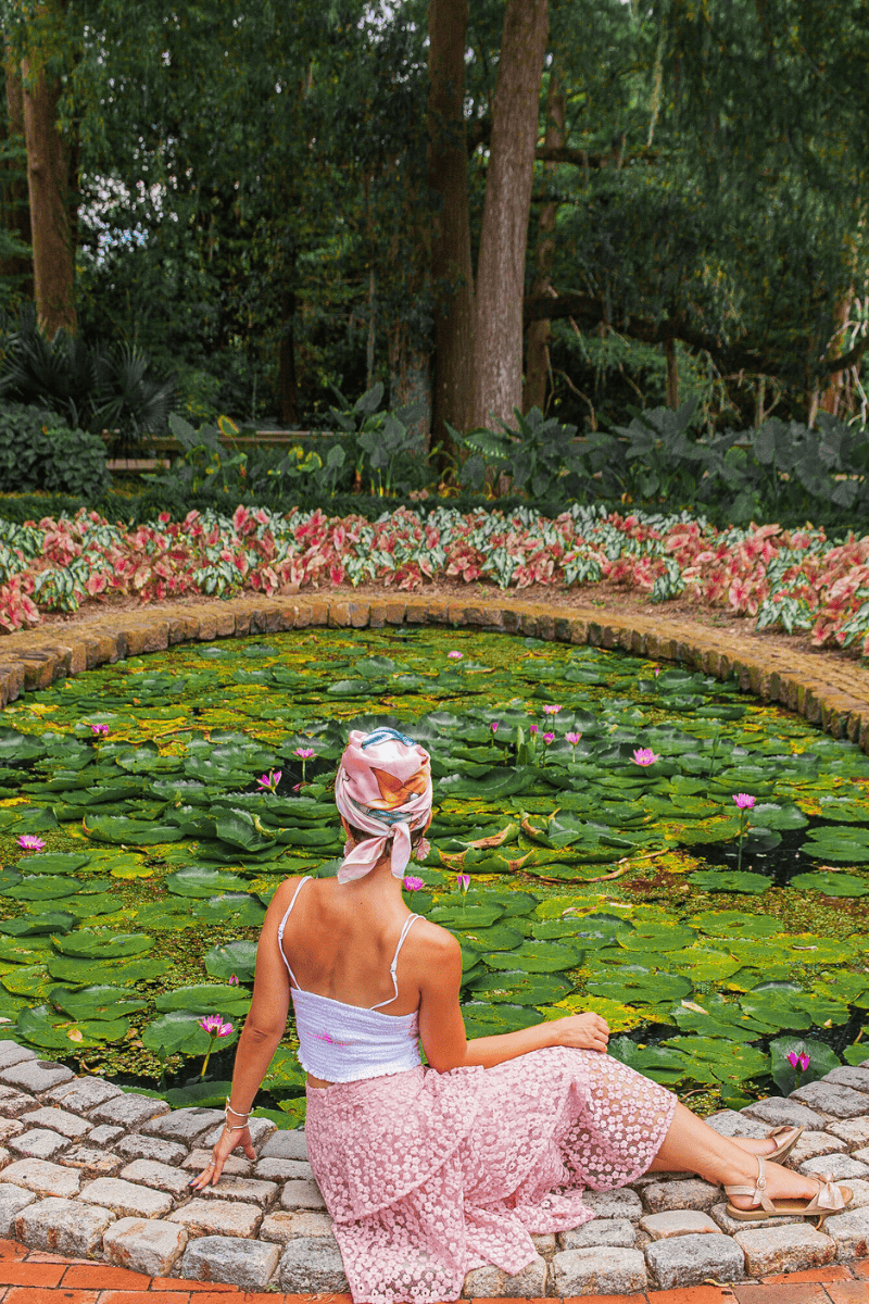 A woamn in turban sitting beside a lily pond.
