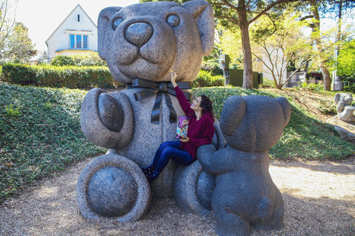 A woman mocking a giant teddy bear statue 
