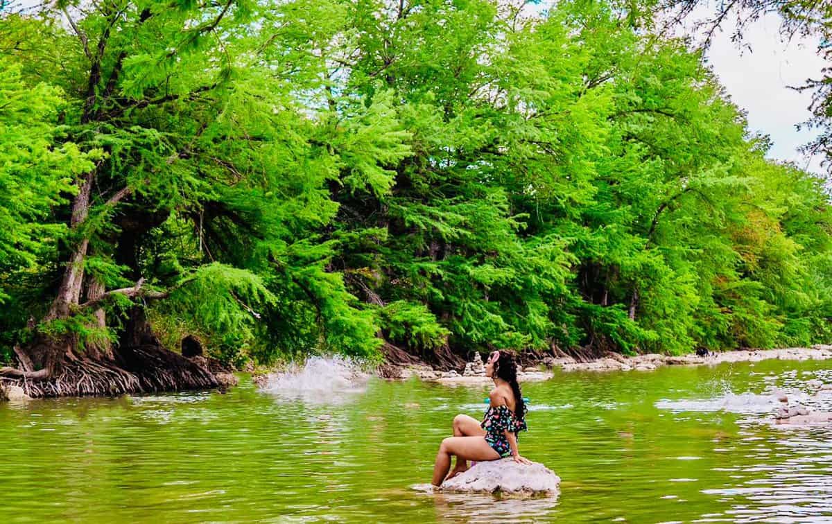 a woman sitting on a rock in a river