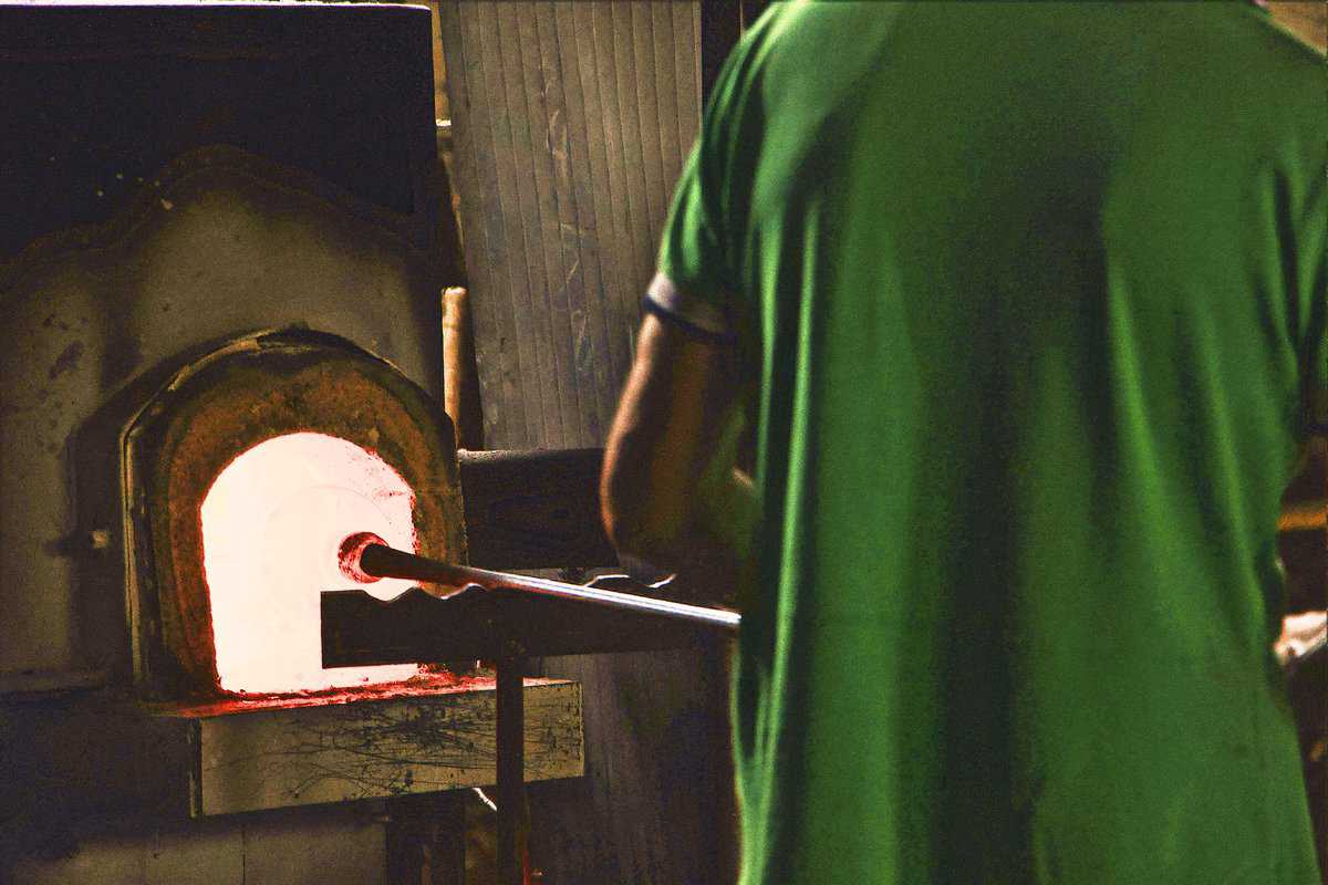 A person in a green shirt stands in front of a glowing furnace