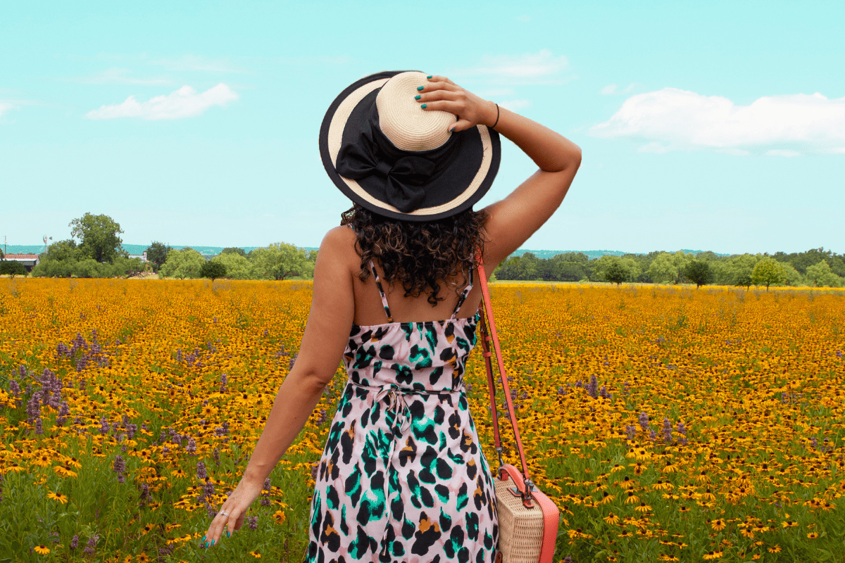 a person in a dress and hat in a field of flowers