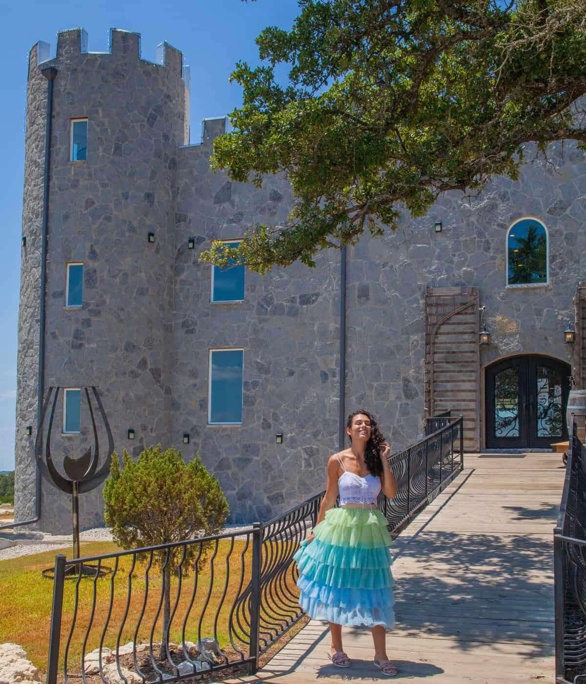 a woman in a dress standing on a walkway in front of a stone building