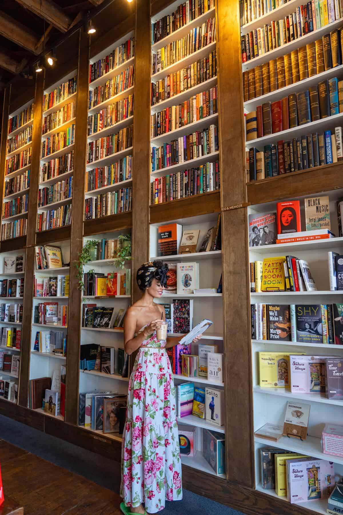 Woman in floral dress standing in front of bookshelf