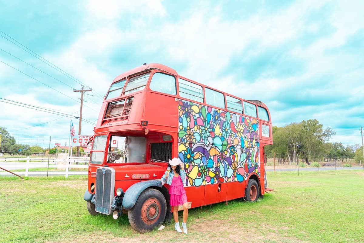 a woman standing next to a red bus