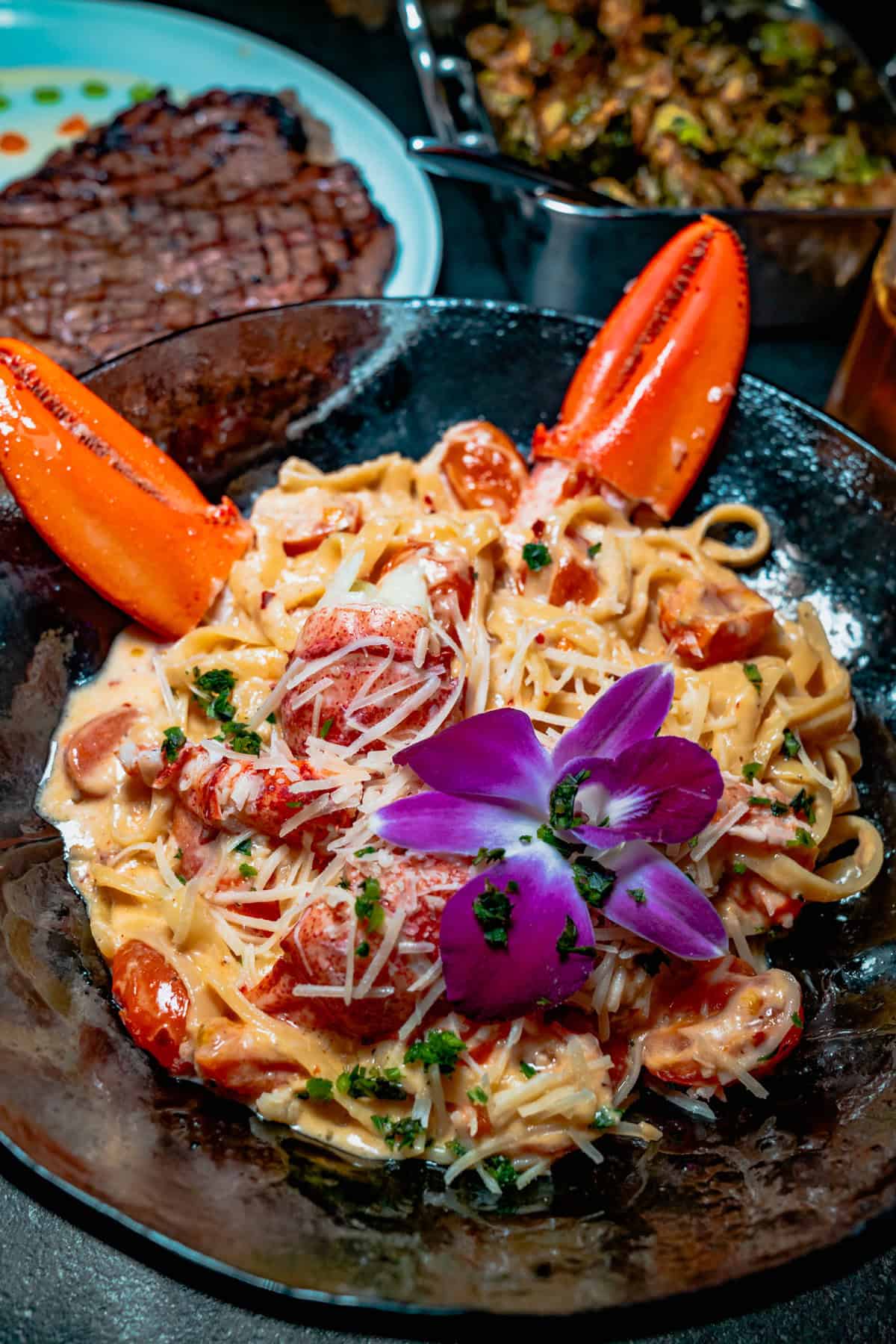 A plate of creamy seafood pasta topped with two lobster claws