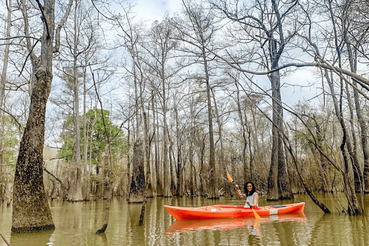 A woman skillfully paddles a kayak down the gentle river