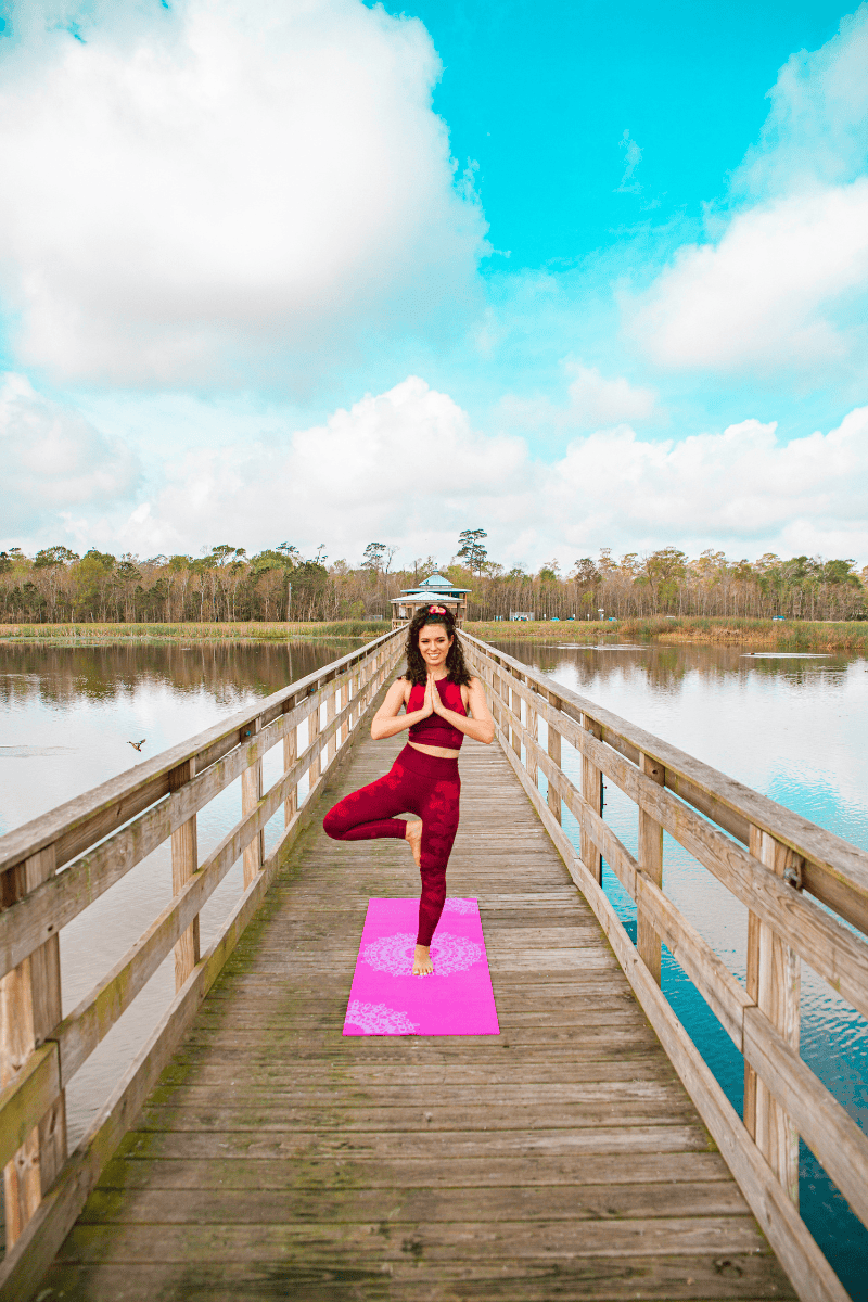 Woman in red practicing yoga on a bridge 