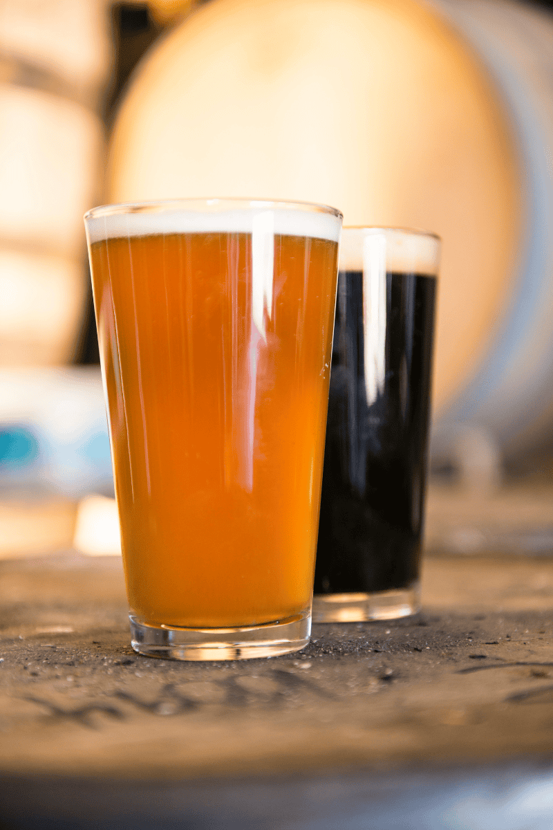 Two glasses of beer on a wooden table.