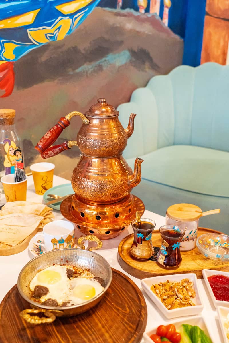 a table with a copper kettle and plates of food