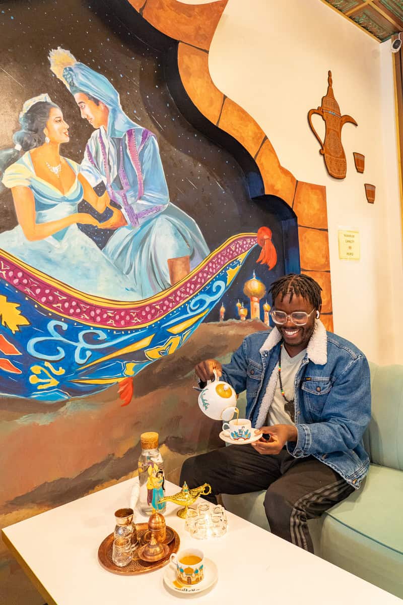 a man sitting on a couch pouring tea into a cup