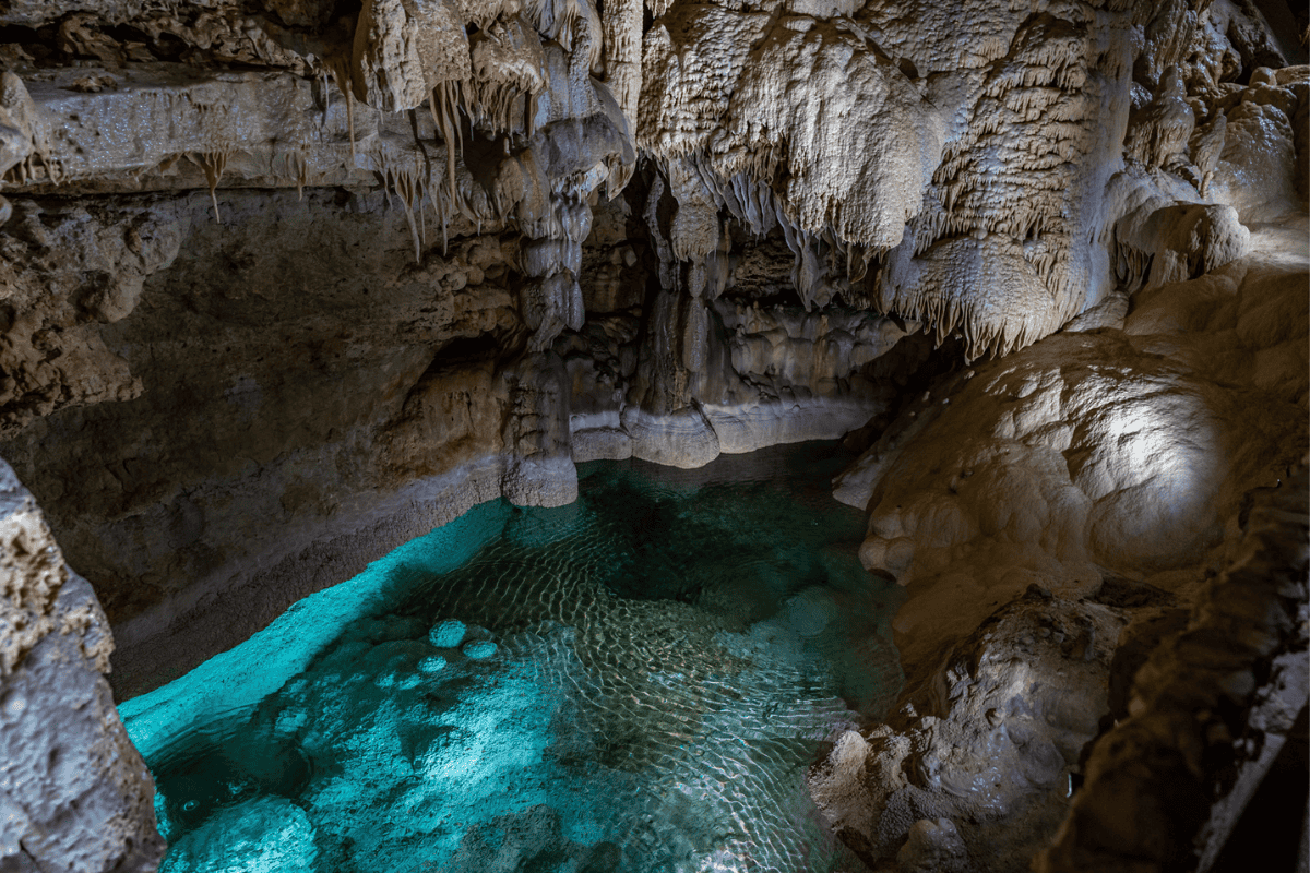 Inside a mystical cave, water gently flows among ancient rocks, creating a serene and enchanting scene.