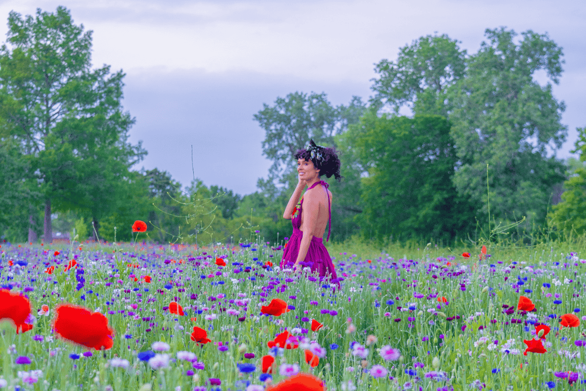 A woman in a purple dress standing in a field of flowers.