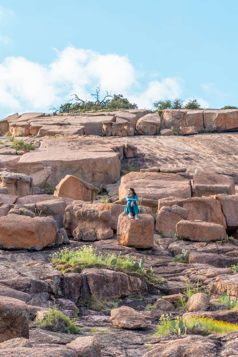 A woman enjoying a peaceful moment, sitting on a rock surrounded by nature's beauty.