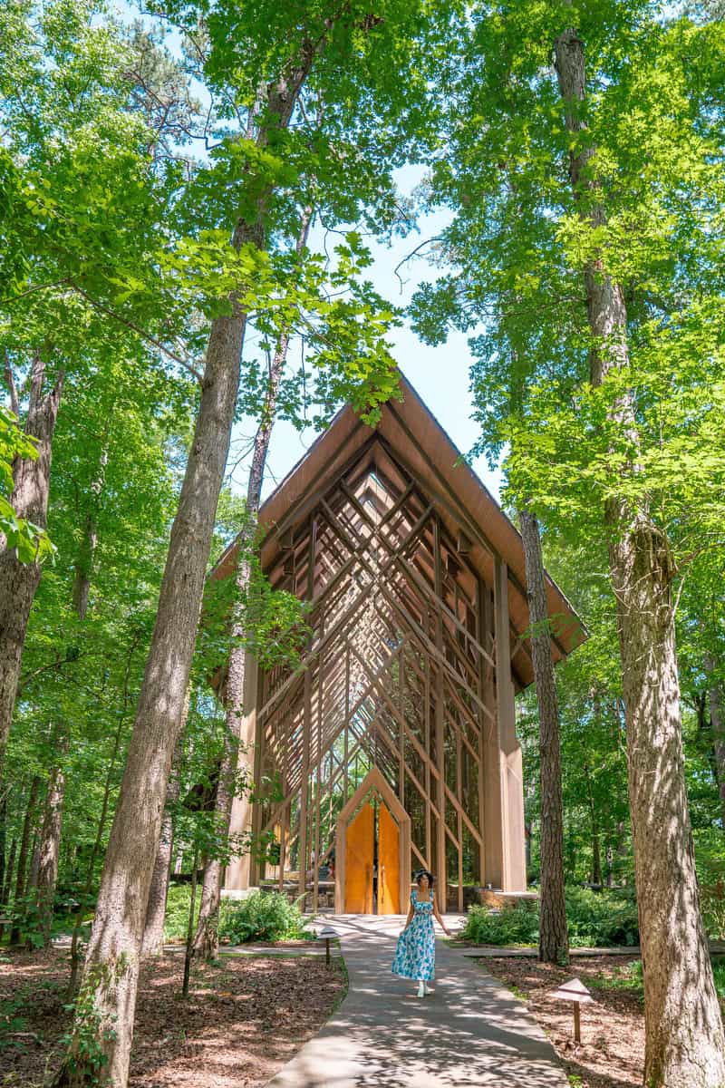 Woman walking through forest with church in background.