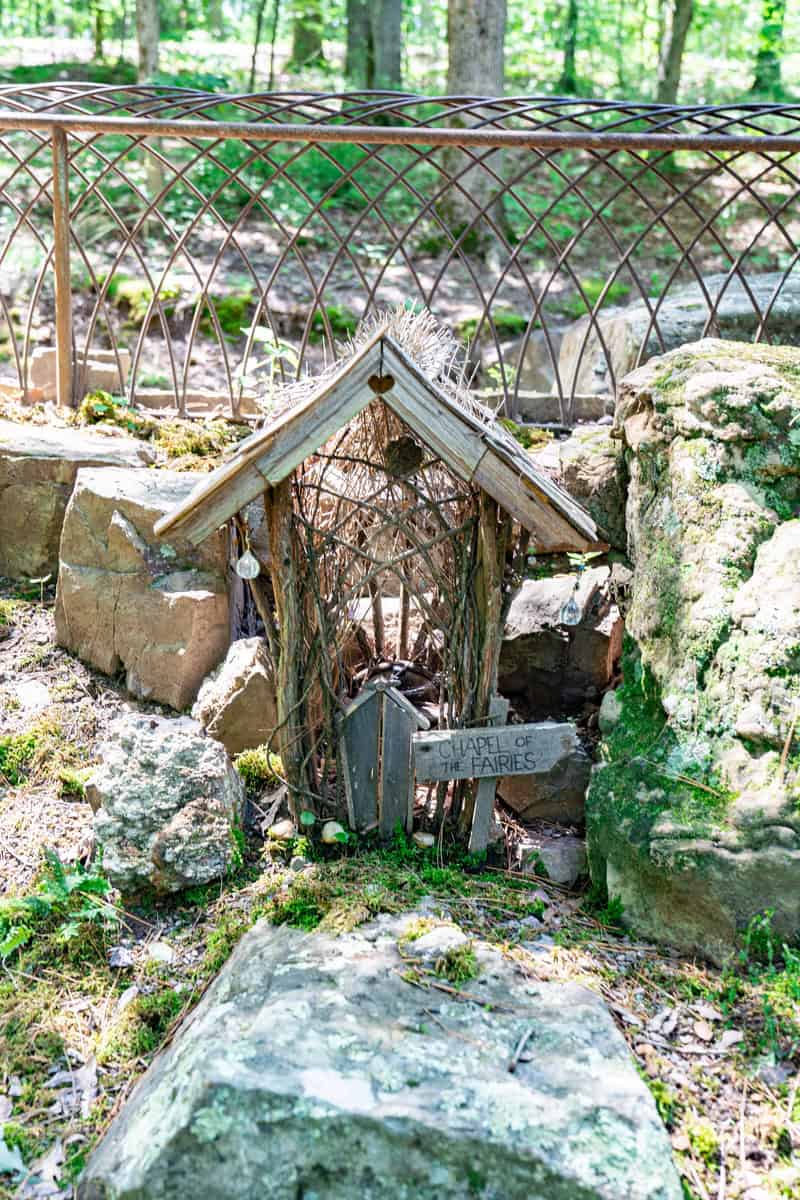 a small wooden house with a sign in front of rocks