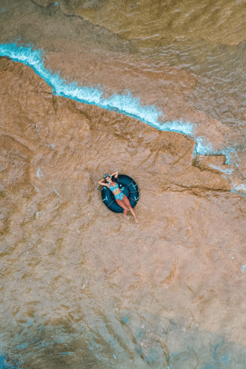 a woman lying on a black inner tube in water