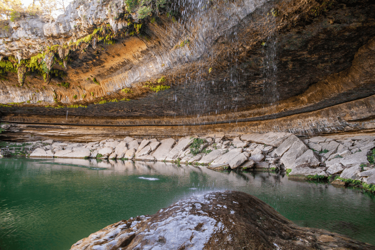 Beautiful waterfall in a deep canyon with trees and rocks.