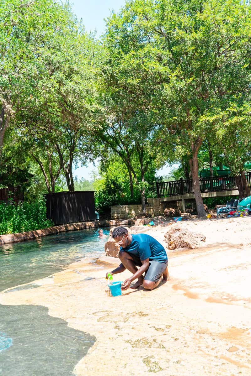 A man playing with water bucket with a sand at a waterpark.