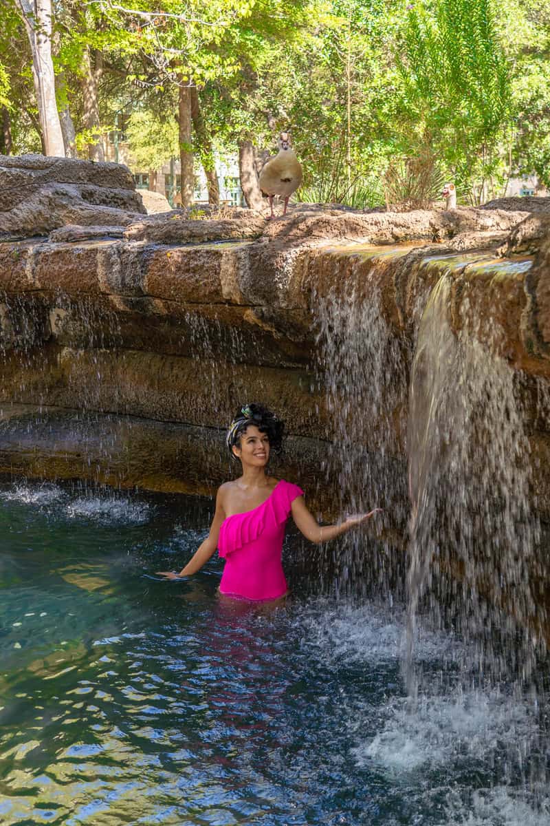 A woman wearing a pink swim suit standing in a pool.