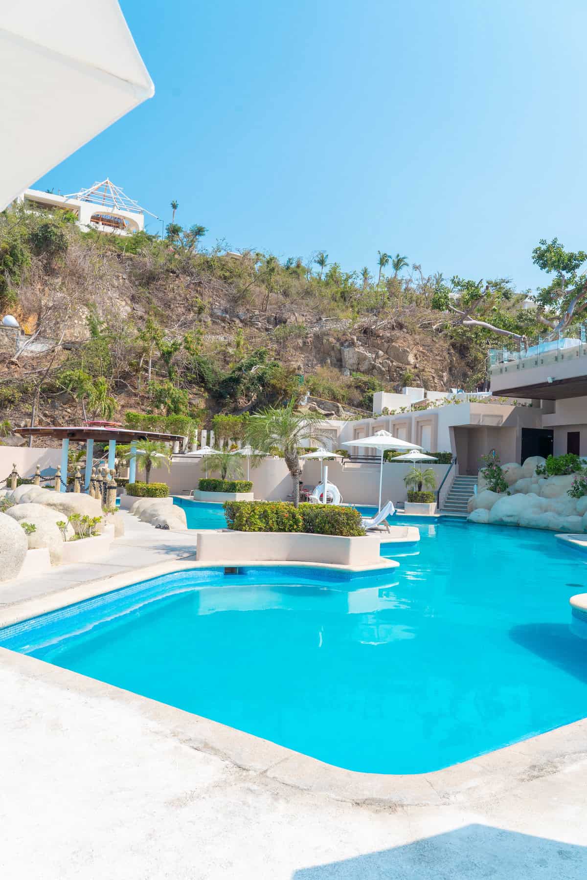 a swimming pool with a large rock wall and a building