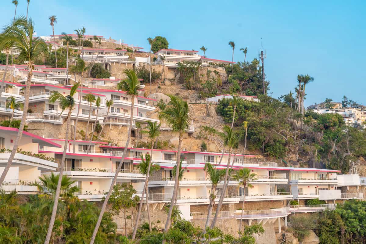 a building on a hill with trees and plants