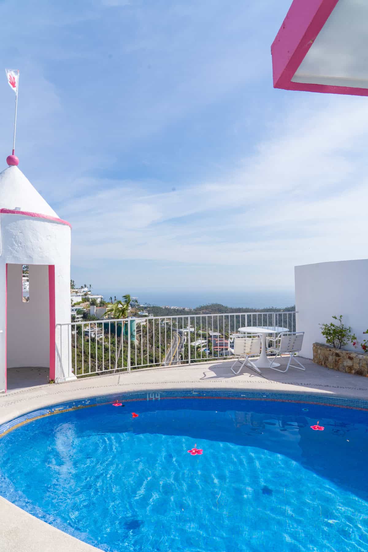 a pool on a deck with a white fence and a white tower