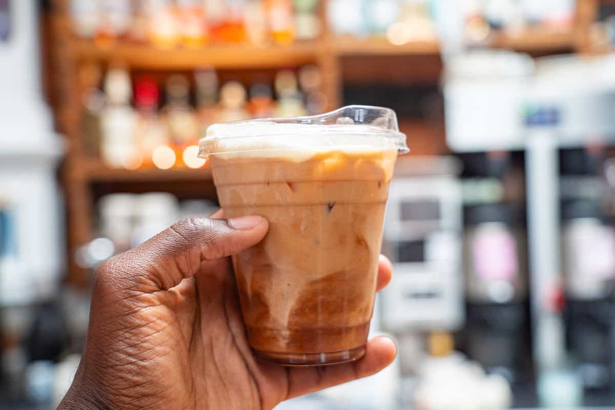 a hand holding a plastic cup of coffee