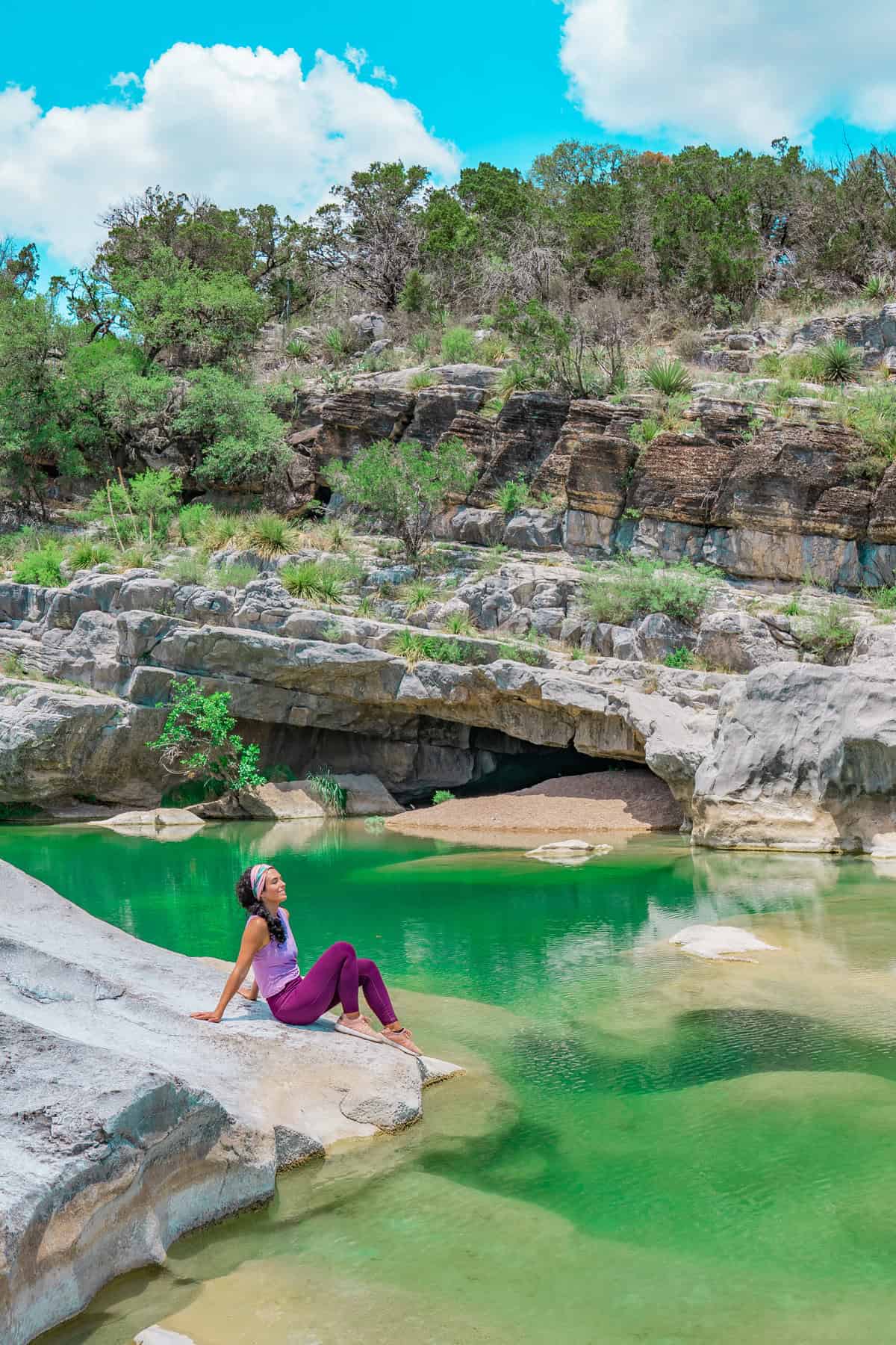 a woman sitting on a rock near water