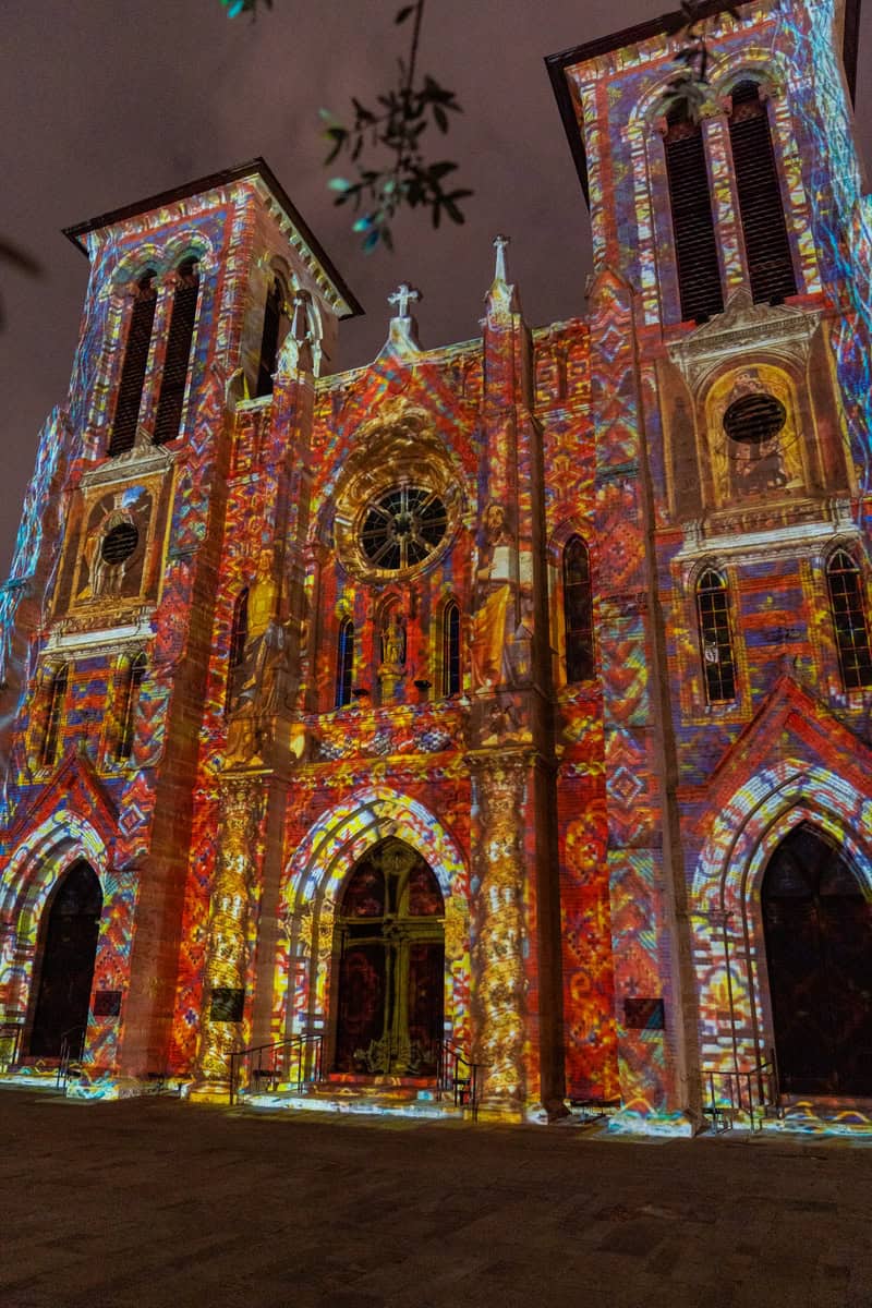 A historic church illuminated with colorful lights at night.