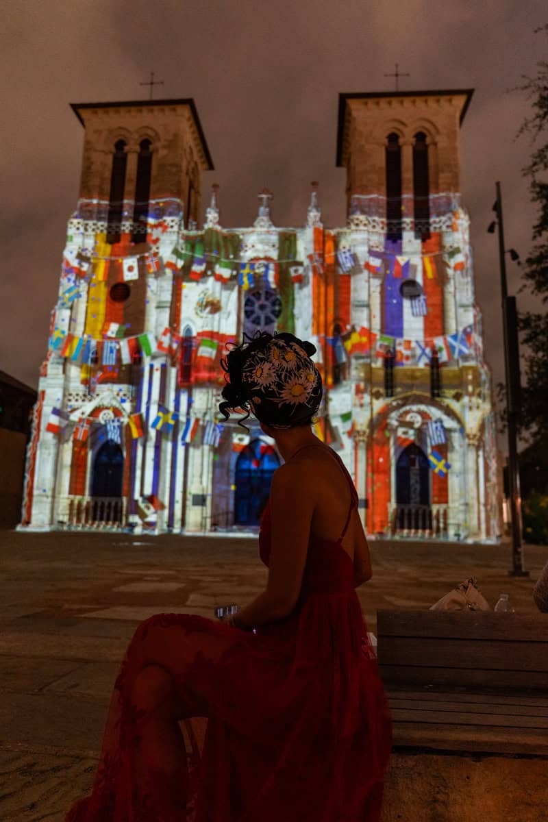 A woman peacefully sitting on a bench in front of a beautiful church.