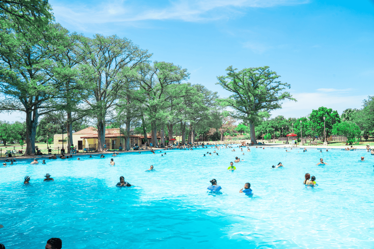  People having fun swimming in a big pool under the bright sun.