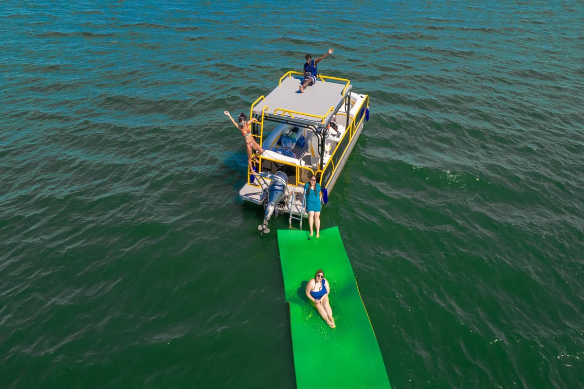 A group of people enjoying a boat ride on a lake with green floating pad.