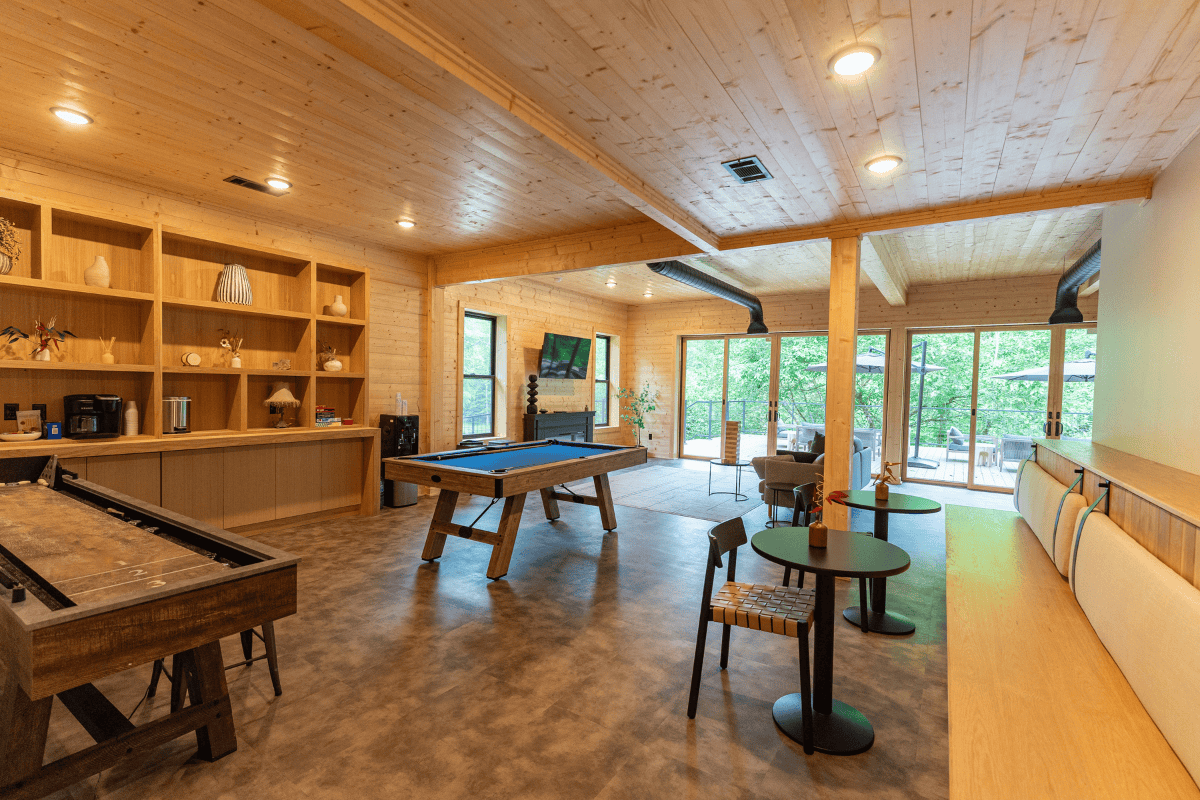 A cozy game room in the club house with a pool table, bar, and comfy couches.