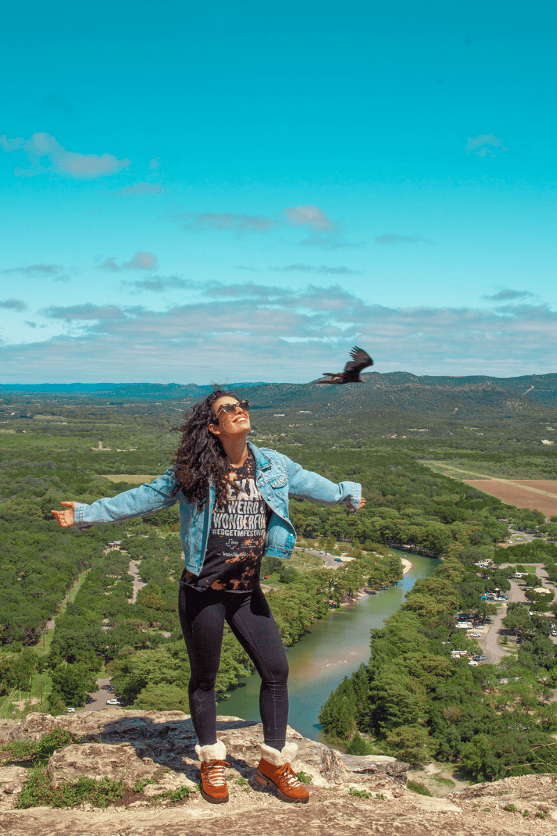 Person with outstretched arms standing on a rocky overlook