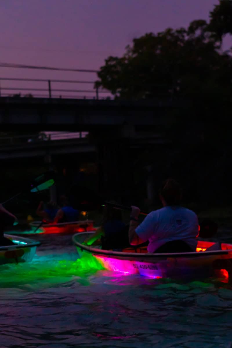 Colorful lights illuminate kayakers as they paddle together 