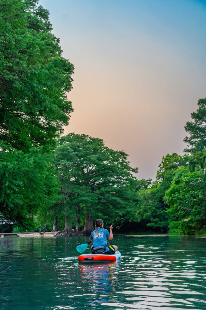 Kayaker enjoying peaceful river surrounded by nature.