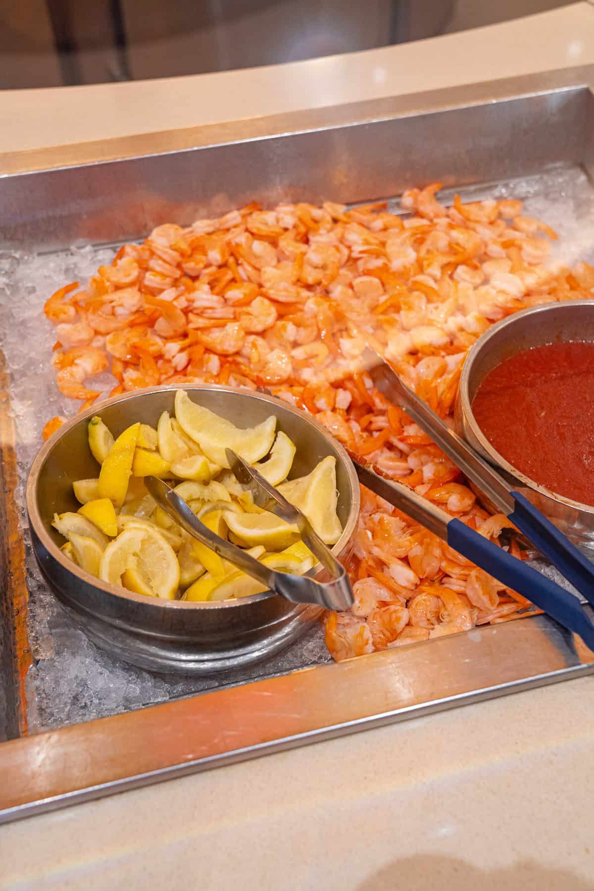 a tray of food with a couple of bowls of food and tongs