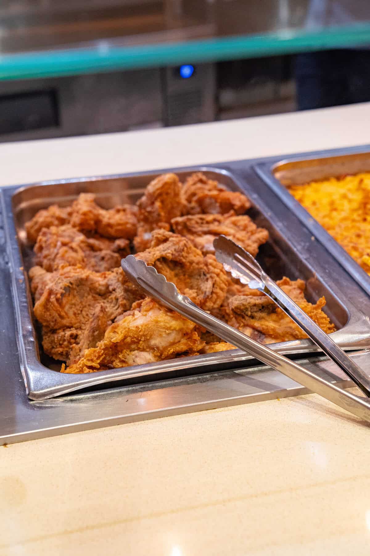 a tray of fried chicken and tongs